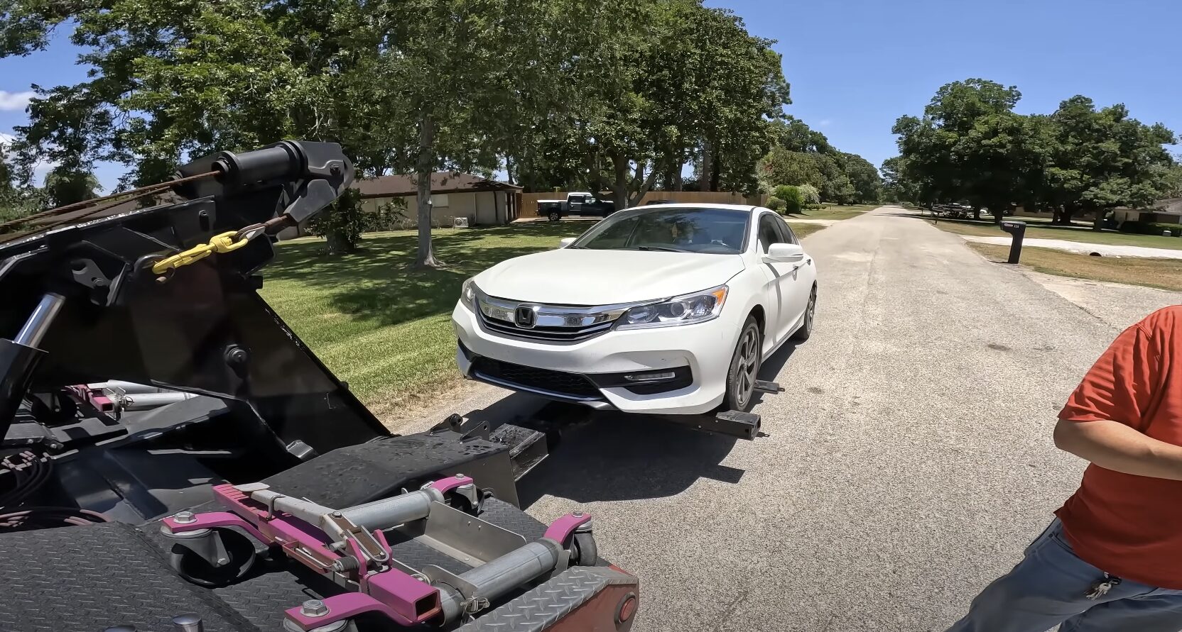 Flatbed towing service providing safe transport for passenger vehicles White Honda sedan being safely loaded onto flatbed tow truck for damage-free transport