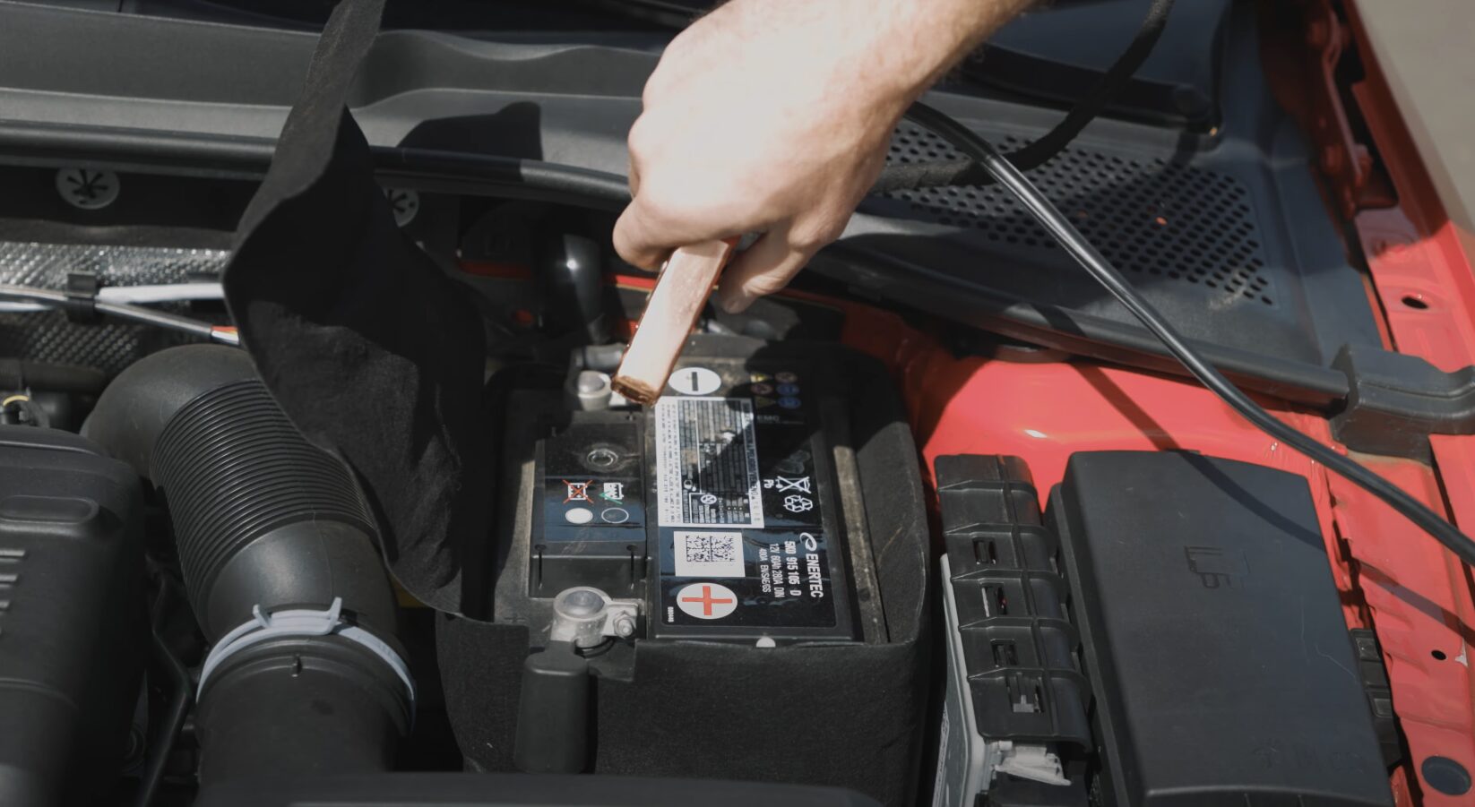 Roadside assistance technician jump starting car battery with professional equipment