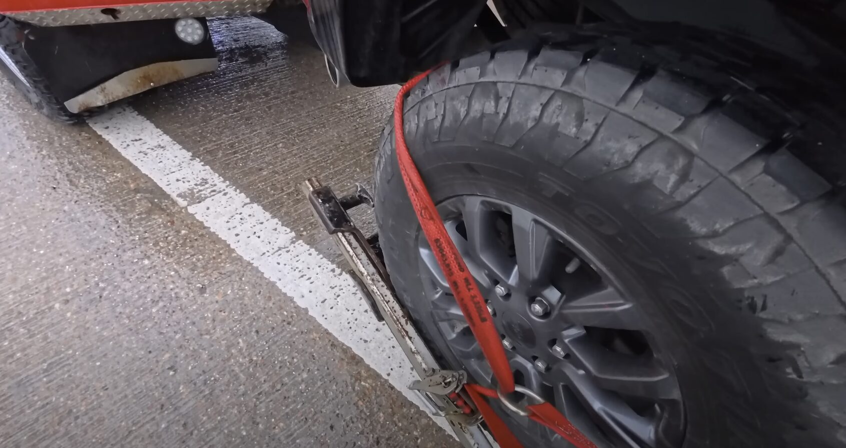 Emergency vehicle recovery and towing service in Woodridge, IL Red pickup truck being secured on professional tow truck equipment for safe emergency transport